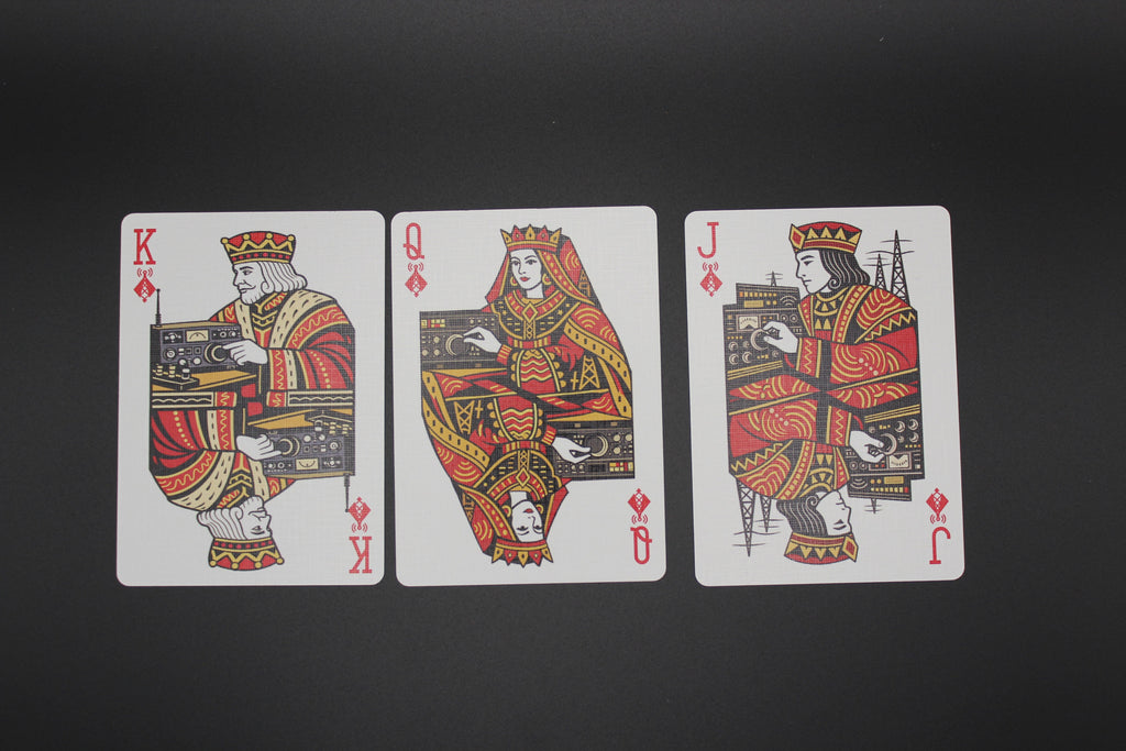 Three playing cards featuring kings, queens, and jacks on a black background