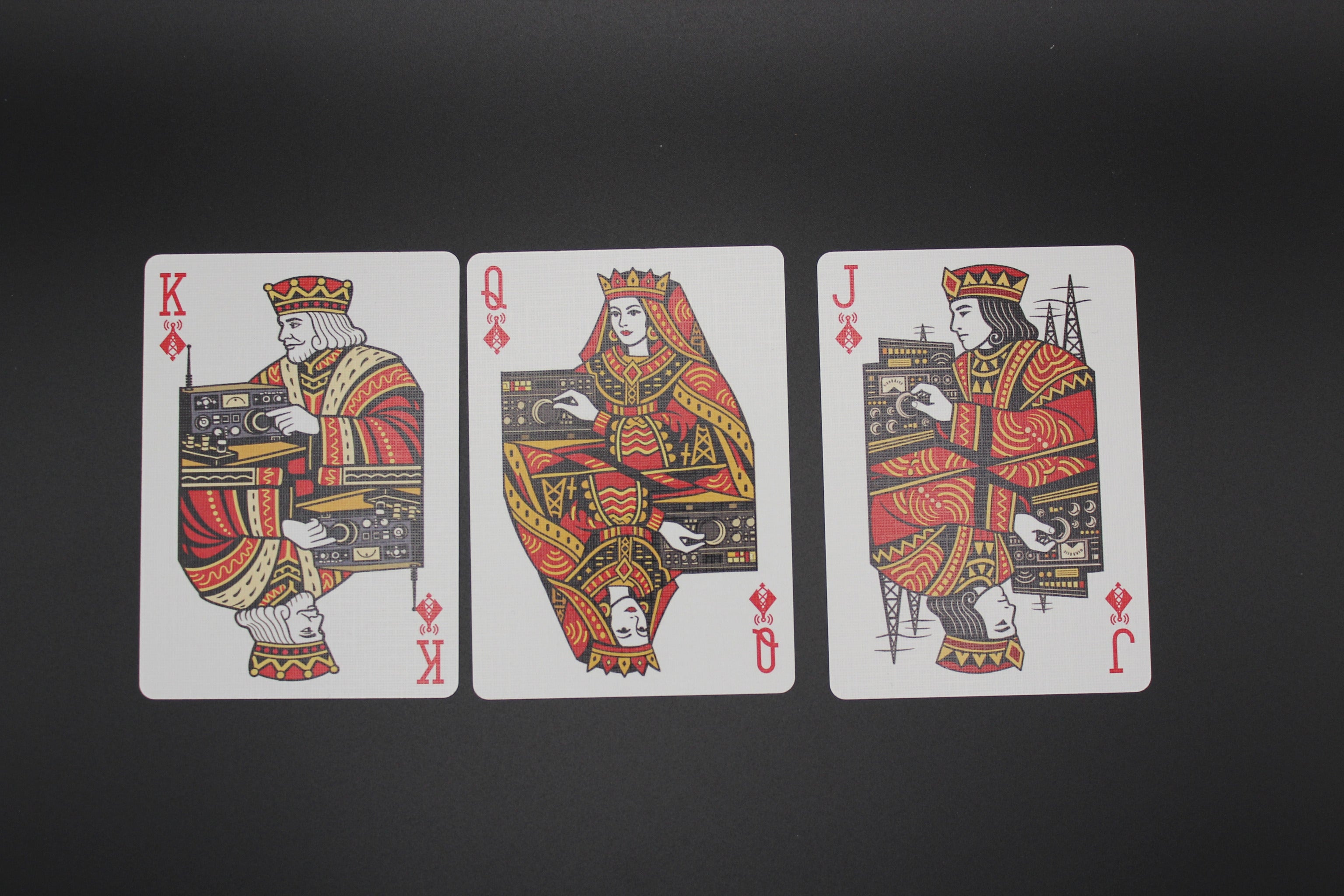Three playing cards featuring kings, queens, and jacks on a black background