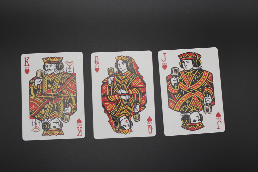 Three playing cards featuring King, Queen, and Jack of Hearts on a black background